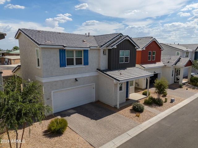 view of front of property with an attached garage, stucco siding, a tiled roof, decorative driveway, and board and batten siding