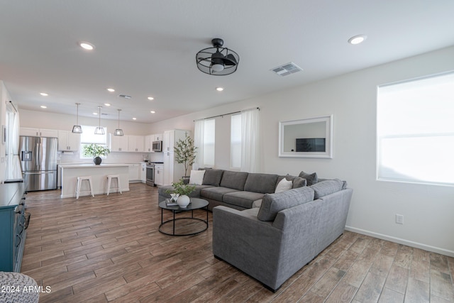 living room with visible vents, recessed lighting, baseboards, and wood finished floors