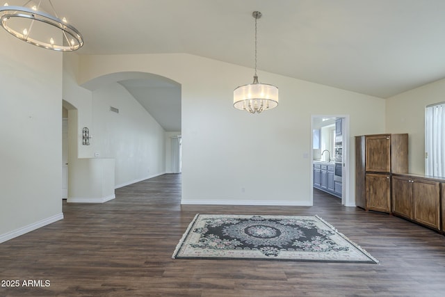 unfurnished dining area featuring vaulted ceiling, dark hardwood / wood-style floors, an inviting chandelier, and sink