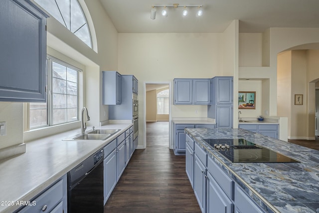 kitchen featuring black appliances, sink, dark hardwood / wood-style floors, a towering ceiling, and blue cabinetry