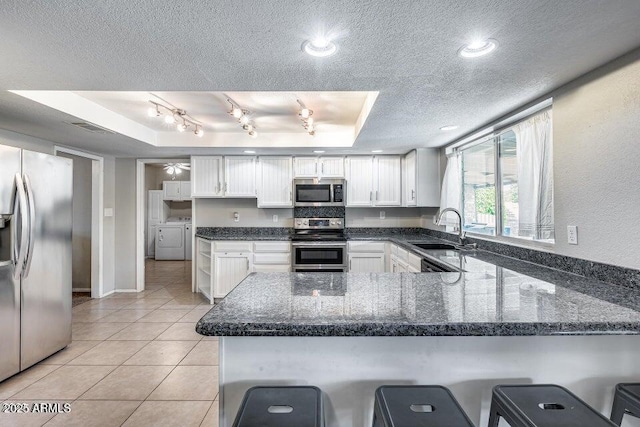 3102 W Betty Elyse Ln, Phoenix, AZ 85053 - kitchen with appliances with stainless steel finishes, a textured ceiling, a tray ceiling, a peninsula, and white cabinets