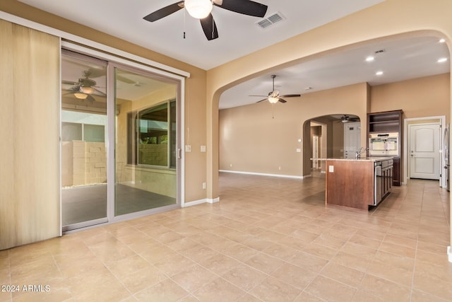 kitchen featuring ceiling fan, sink, oven, a kitchen island with sink, and light tile patterned floors