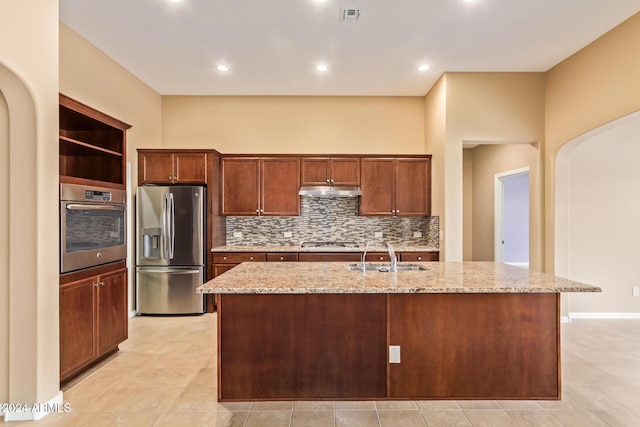 kitchen with a kitchen island with sink, sink, stainless steel appliances, and light stone counters