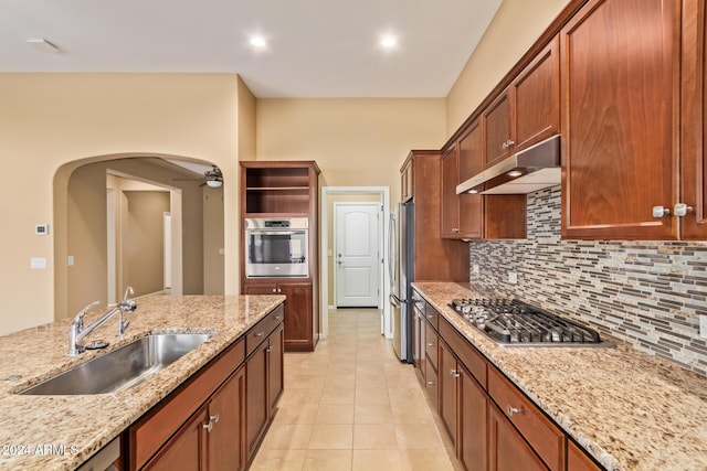 kitchen with sink, decorative backsplash, light tile patterned flooring, light stone counters, and stainless steel appliances