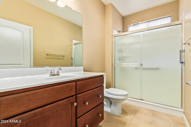 bathroom featuring tile patterned flooring, vanity, toilet, and a shower with shower door