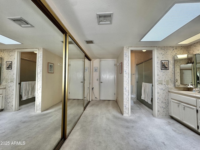 bathroom featuring wallpapered walls, visible vents, and a skylight