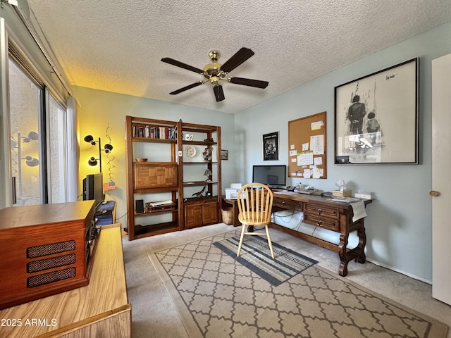 carpeted office featuring a textured ceiling and a ceiling fan