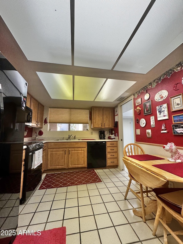 kitchen with a sink, black appliances, light tile patterned floors, and light countertops