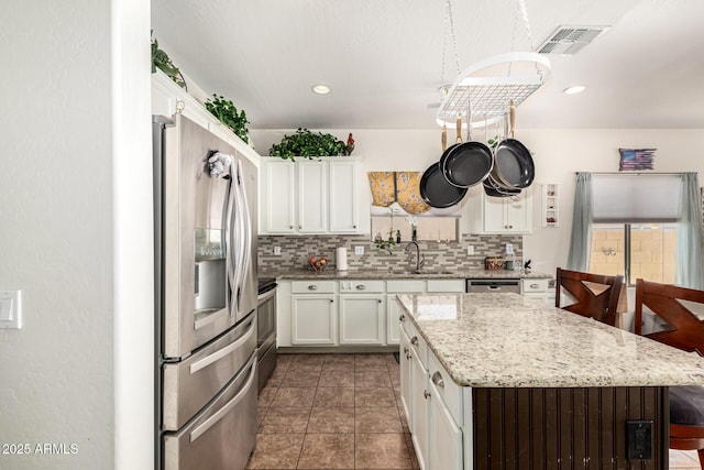 kitchen with sink, stainless steel appliances, white cabinets, and backsplash