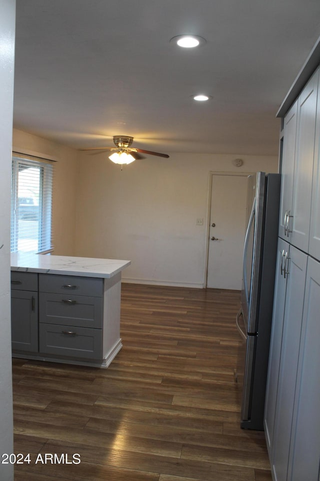 kitchen with gray cabinets, light stone counters, dark hardwood / wood-style flooring, ceiling fan, and stainless steel fridge