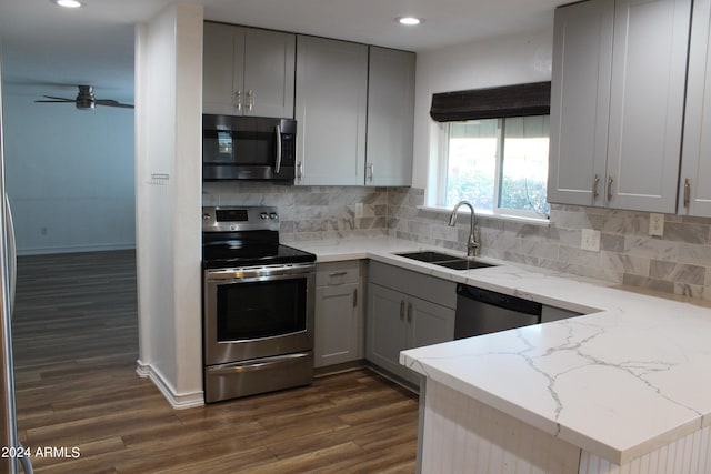 kitchen featuring light stone counters, dark wood-type flooring, sink, gray cabinetry, and stainless steel appliances