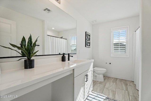 bathroom with vanity, toilet, and a wealth of natural light