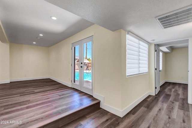 interior space featuring a textured ceiling, french doors, and dark wood-type flooring