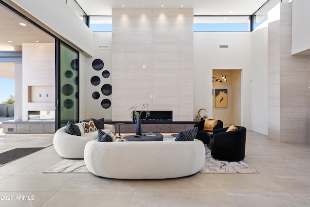 living room with visible vents, expansive windows, a towering ceiling, and a high end fireplace