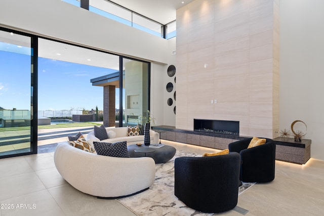 interior space featuring expansive windows, a high ceiling, and a tiled fireplace