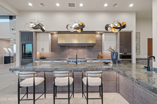 kitchen with appliances with stainless steel finishes, a breakfast bar area, modern cabinets, and visible vents