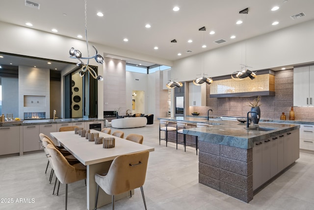 kitchen featuring a high ceiling, a spacious island, visible vents, decorative backsplash, and modern cabinets