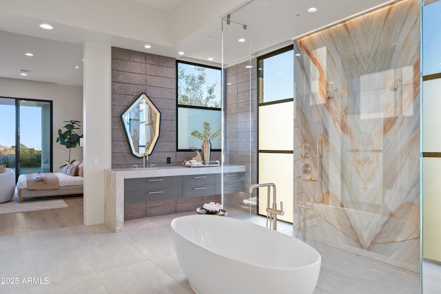 bathroom featuring ensuite bath, tile patterned flooring, vanity, a freestanding tub, and recessed lighting