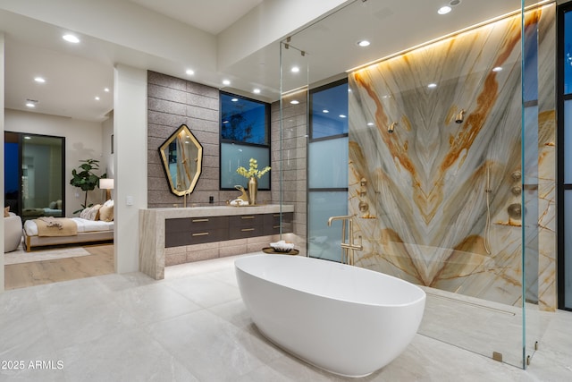 bathroom with a marble finish shower, connected bathroom, a soaking tub, vanity, and recessed lighting