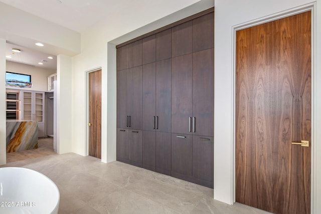 full bath featuring a walk in closet, a freestanding bath, and recessed lighting