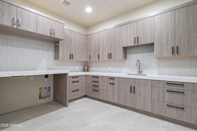 kitchen with tasteful backsplash, light countertops, visible vents, light brown cabinetry, and a sink