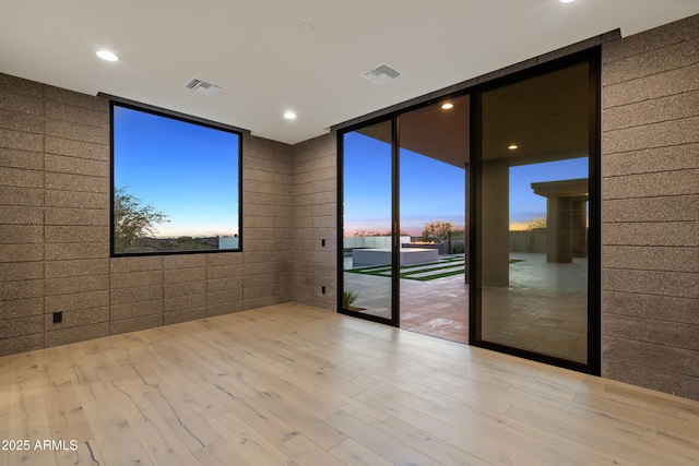 empty room with expansive windows, wood finished floors, visible vents, and recessed lighting