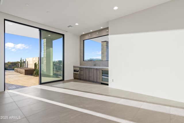 unfurnished room featuring light tile patterned floors, recessed lighting, visible vents, a sink, and beverage cooler