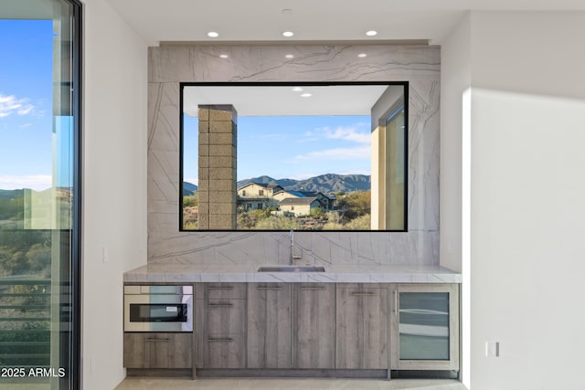 bar with beverage cooler, a mountain view, a sink, and recessed lighting