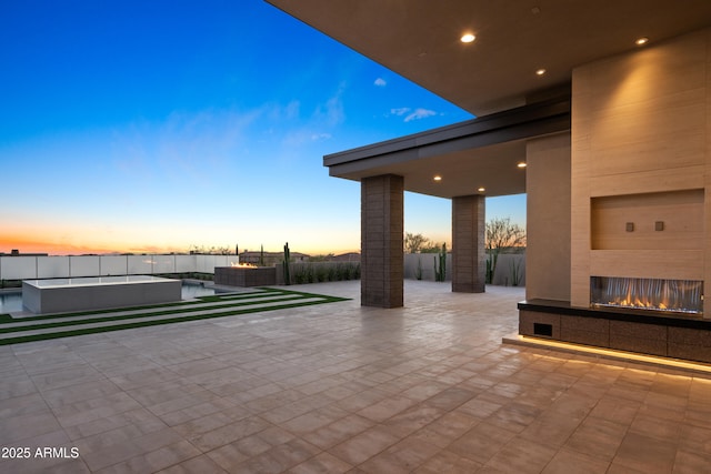 view of patio / terrace featuring a jacuzzi, fence, a fenced in pool, and a multi sided fireplace