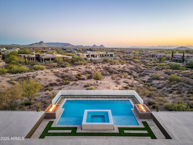 view of pool featuring a patio area, a pool with connected hot tub, a fire pit, and a mountain view