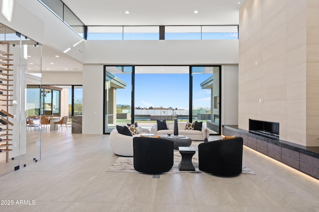 living area with floor to ceiling windows, a fireplace, and a high ceiling