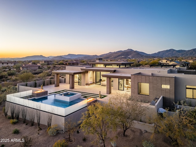 back of property with a pool with connected hot tub, a patio area, a mountain view, and fence