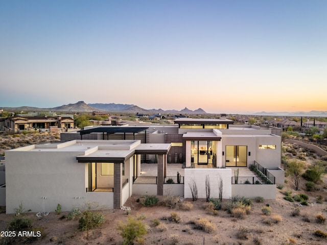 back of property featuring a fenced front yard, a mountain view, and stucco siding