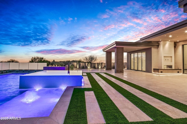 pool at dusk featuring a patio area, fence, and a fenced in pool