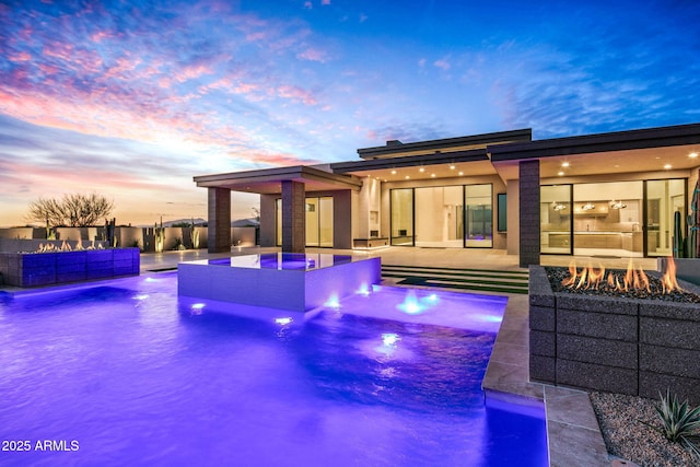 view of pool with an outdoor living space with a fire pit, a pool with connected hot tub, a patio area, and area for grilling