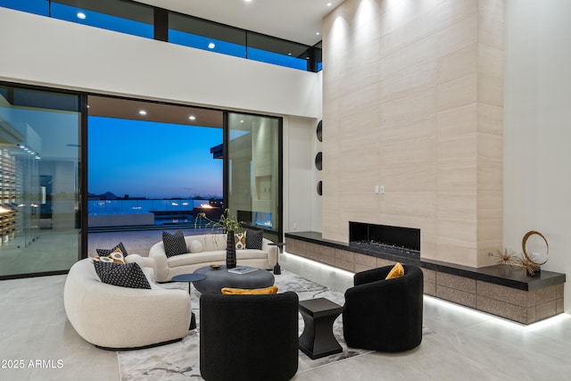 living room with a wall of windows, concrete floors, a towering ceiling, and a premium fireplace