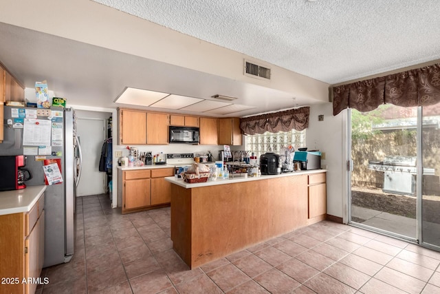 4957 W Onyx Ave, Glendale, AZ 85302 - kitchen with black microwave, a peninsula, light countertops, freestanding refrigerator, and plenty of natural light