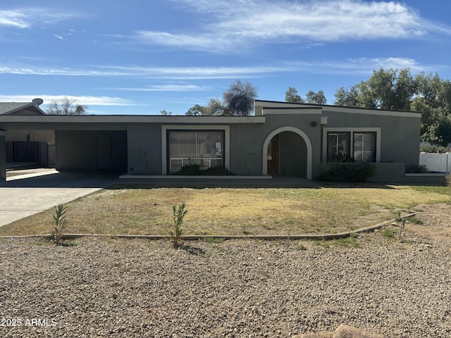 view of front of property featuring driveway, a front yard, an attached carport, and stucco siding