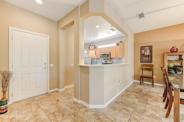 16857 W Villagio Dr, Surprise, AZ 85387 - kitchen featuring stainless steel microwave, light brown cabinetry, light countertops, tasteful backsplash, and light tile patterned flooring