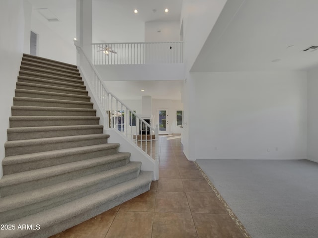 stairway with tile patterned flooring and a high ceiling