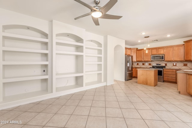 kitchen with ceiling fan, stainless steel appliances, built in features, and a kitchen island