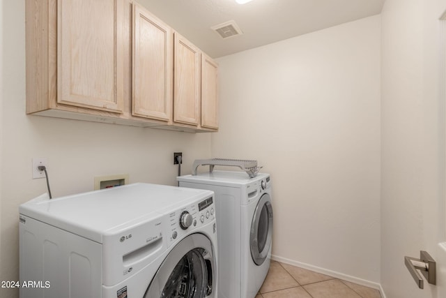 laundry area with light tile patterned flooring, washer and dryer, and cabinets