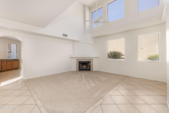 unfurnished living room featuring light tile patterned flooring, a tiled fireplace, ceiling fan, and high vaulted ceiling