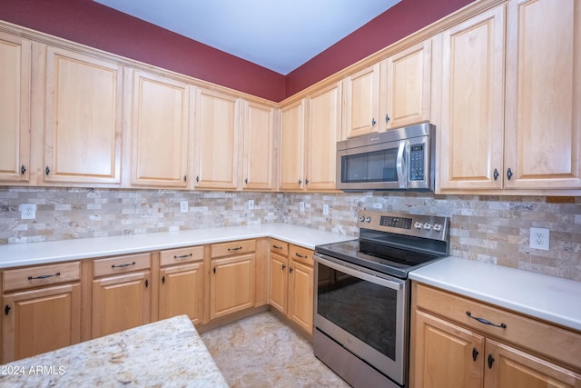 kitchen with backsplash, light tile patterned floors, and appliances with stainless steel finishes