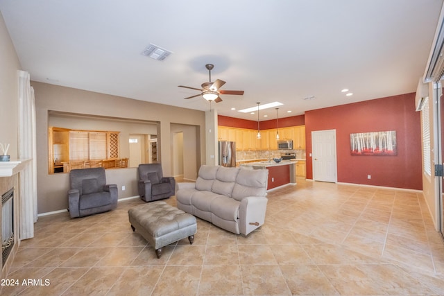 tiled living room featuring a fireplace and ceiling fan