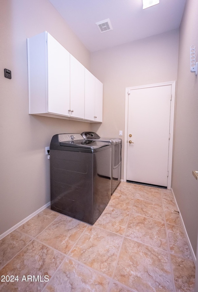 clothes washing area featuring cabinets and separate washer and dryer