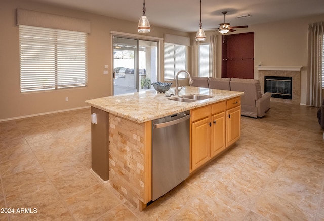 kitchen featuring sink, stainless steel dishwasher, hanging light fixtures, and an island with sink