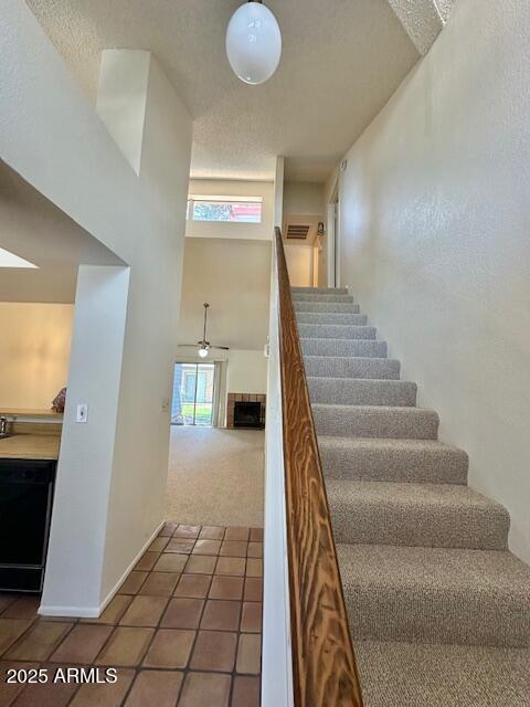 14002 N 49th Ave Unit 1021, Glendale, AZ 85306 - stairway with tile patterned floors, carpet floors, a fireplace, and a high ceiling
