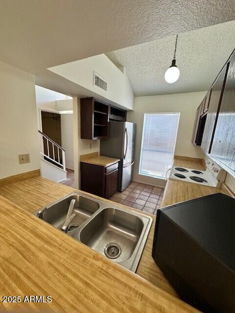 14002 N 49th Ave Unit 1021, Glendale, AZ 85306 - kitchen featuring white range with electric stovetop, freestanding refrigerator, a textured ceiling, dark brown cabinets, and light countertops