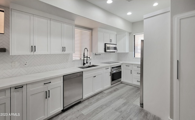 kitchen with tasteful backsplash, appliances with stainless steel finishes, sink, and white cabinets